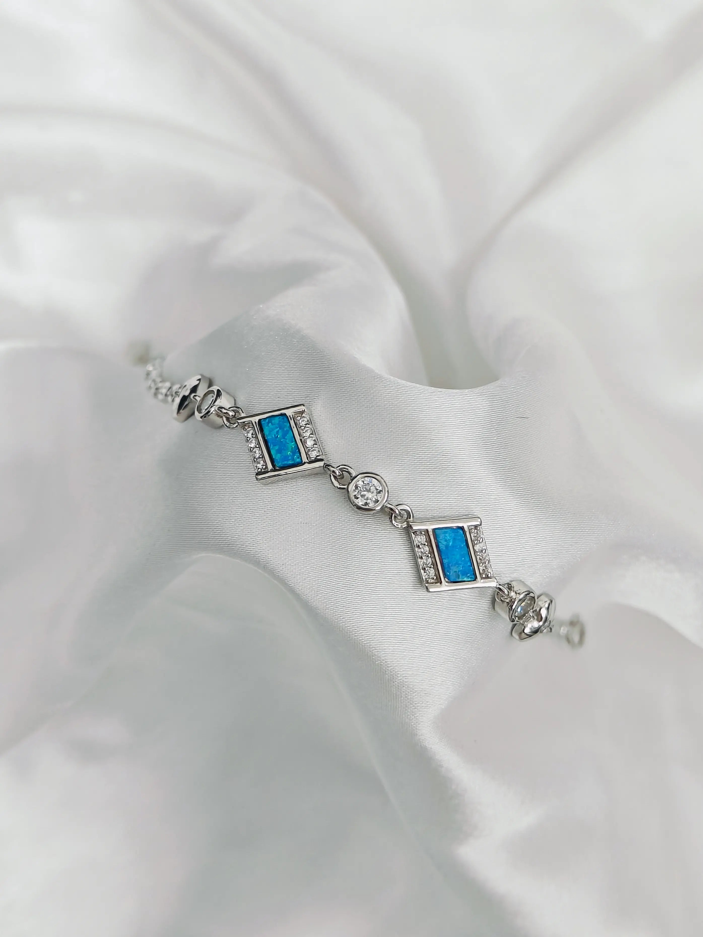 Silver bracelet with blue gemstones on a white fabric background